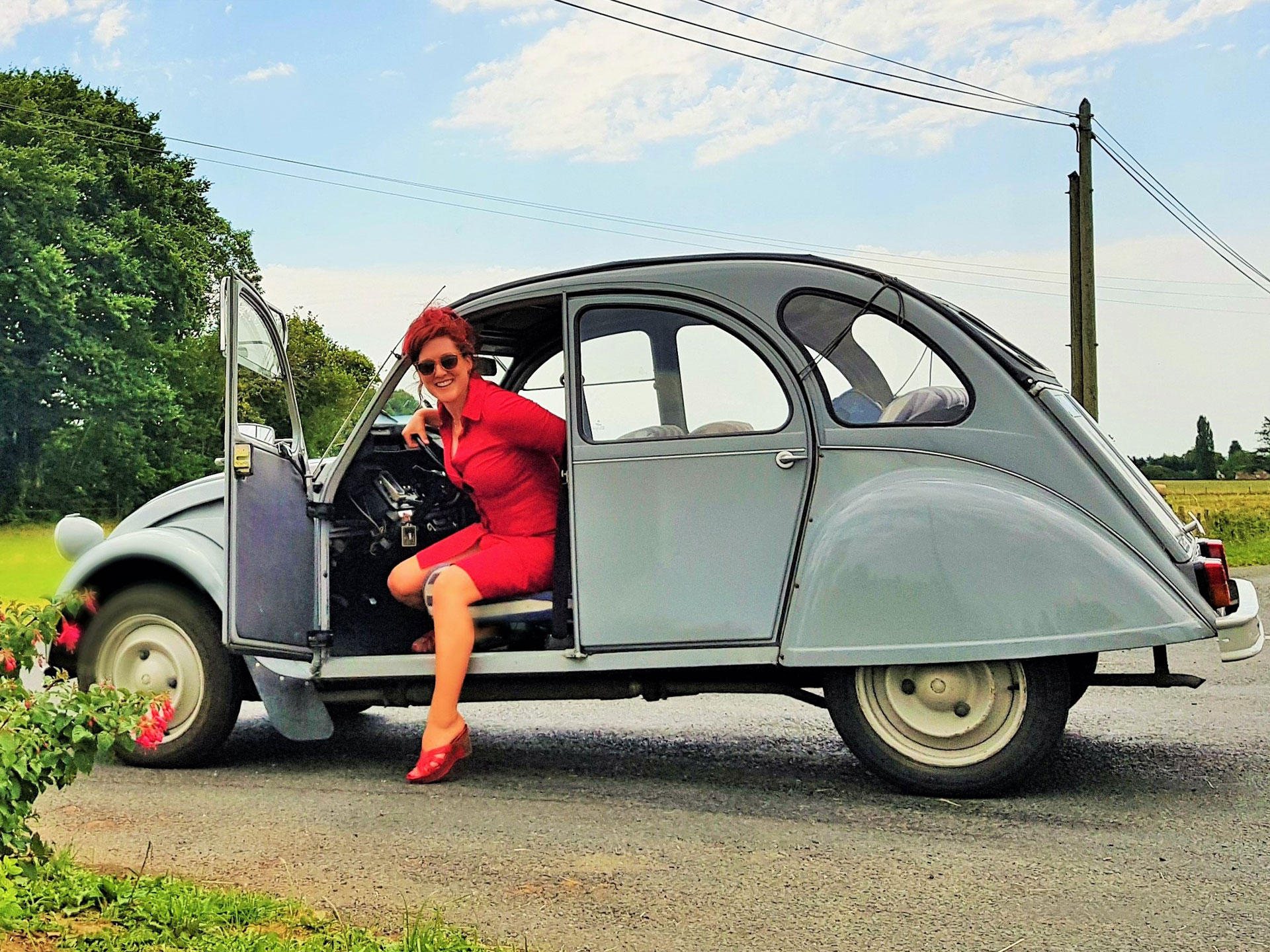 Lois Pryce looking chic stepping out of a blue 2CV