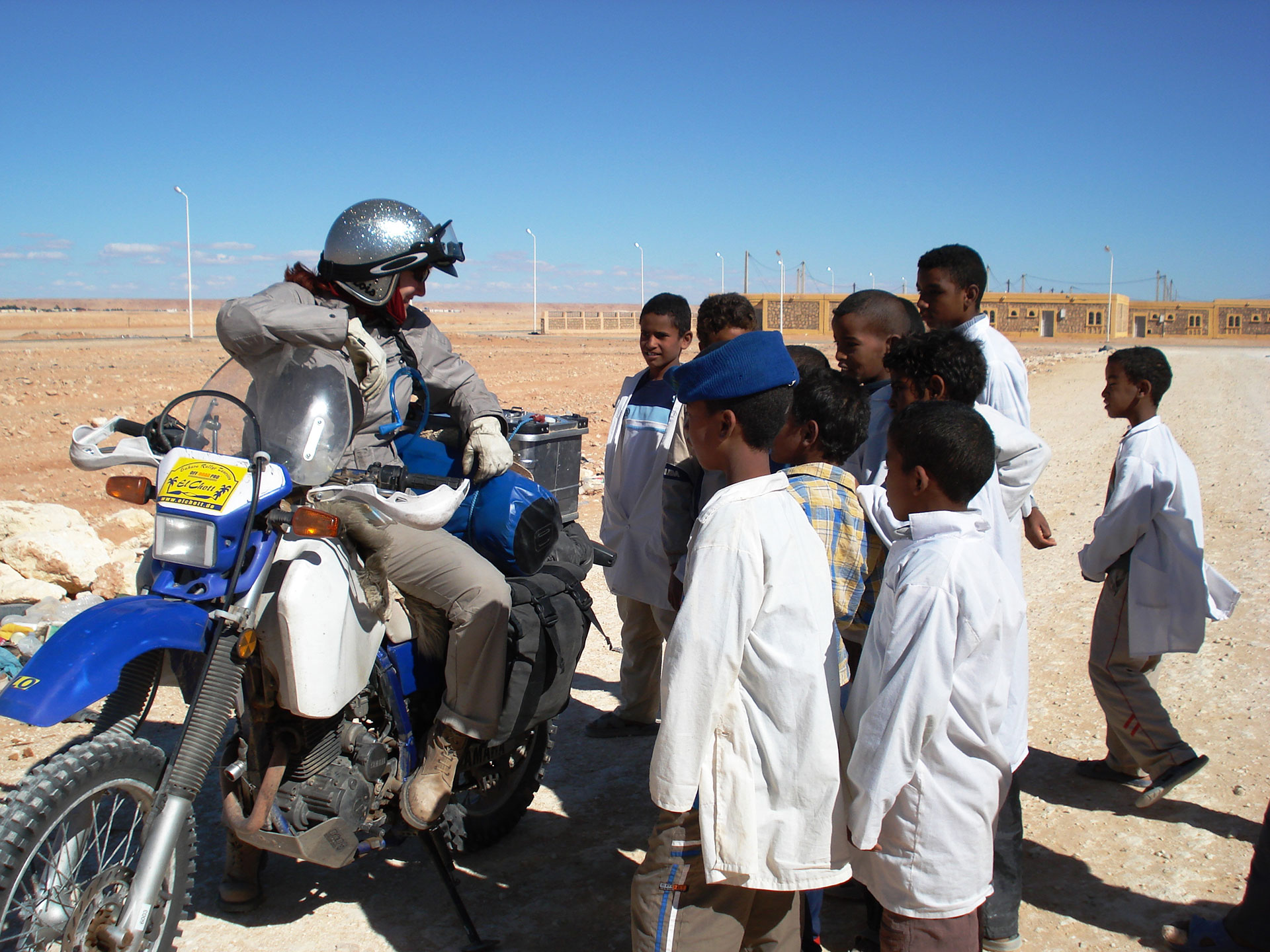 Motorcycle adventurer Lois Pryce in Algeria on her bike talking to a group of children