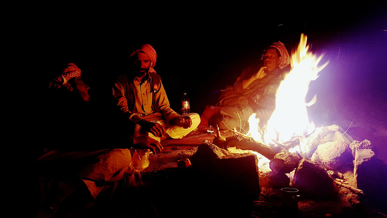 Bonfire in the Sinai desert with men sitting around drinking tea