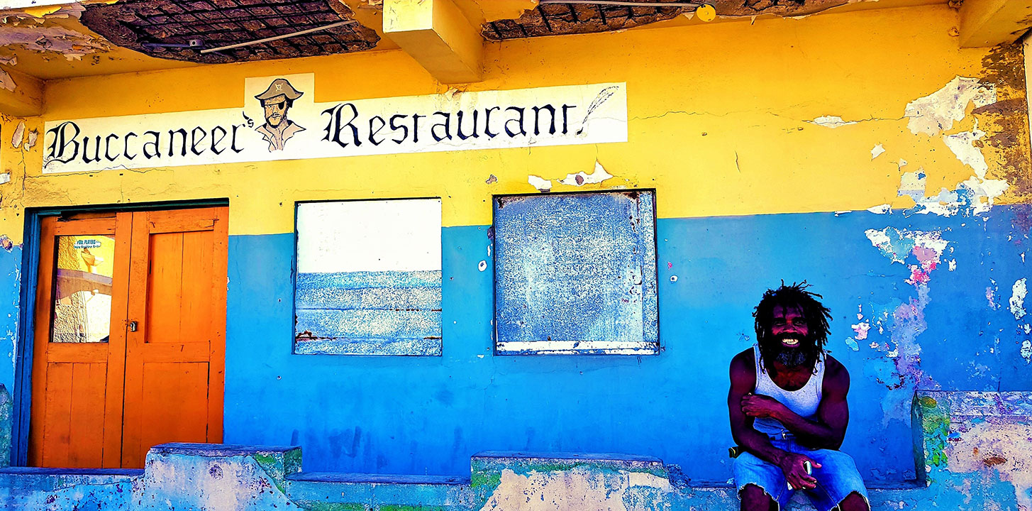 Man with dreadlocks smilling outside the colourful buccaneer Restaurant in Jamaica