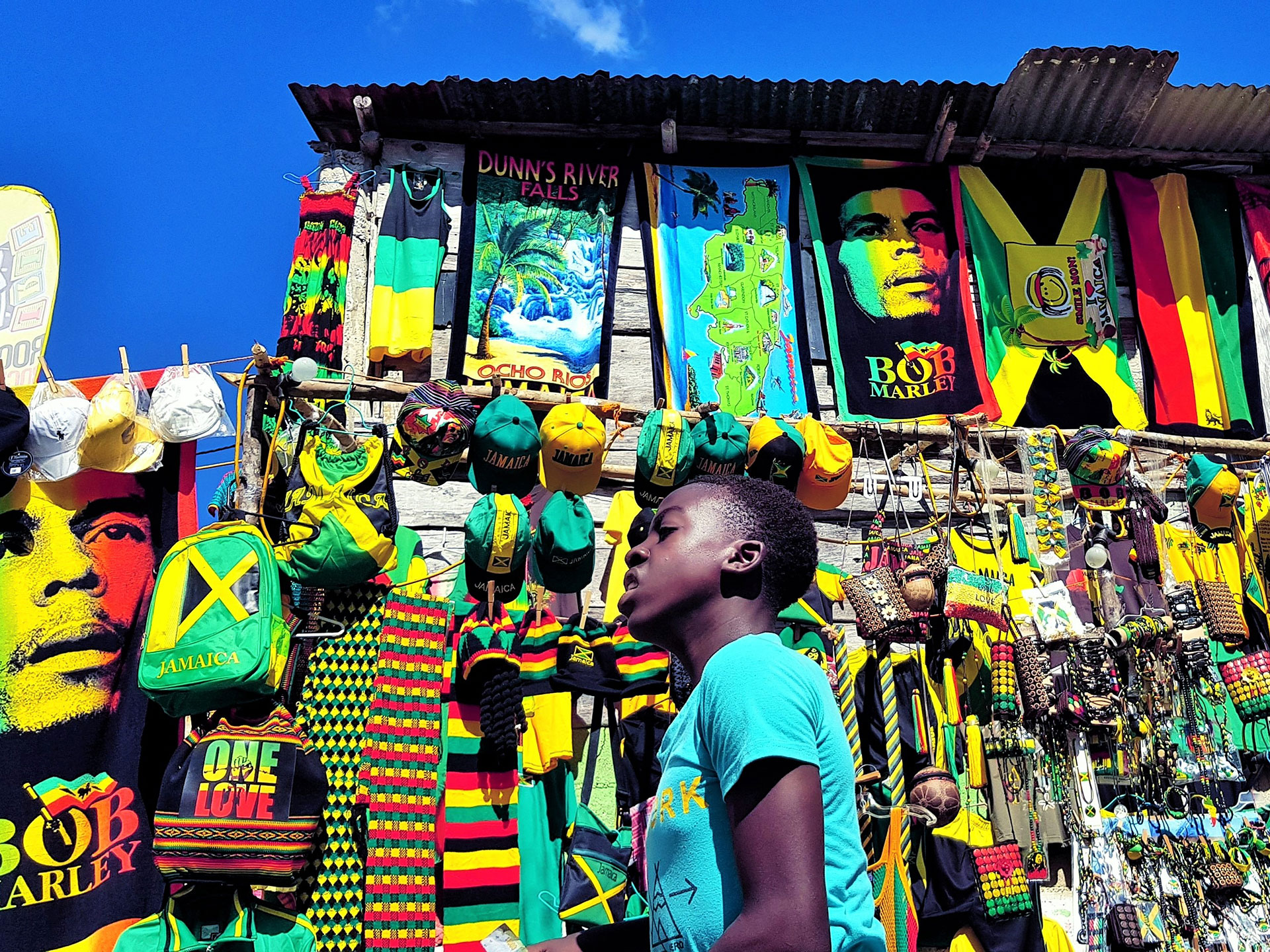 Boy next to a colourful stall selling Bob Marley memorabilia in Jamaica