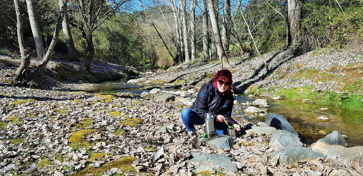 Adventure author Lois Pryce making tea by a river in a kelly kettle