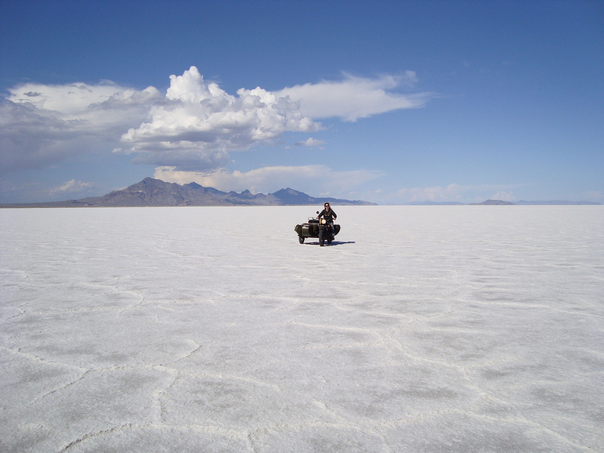 Lois Pryce riding across the bonneville salt flats with a motorbike and sidecar