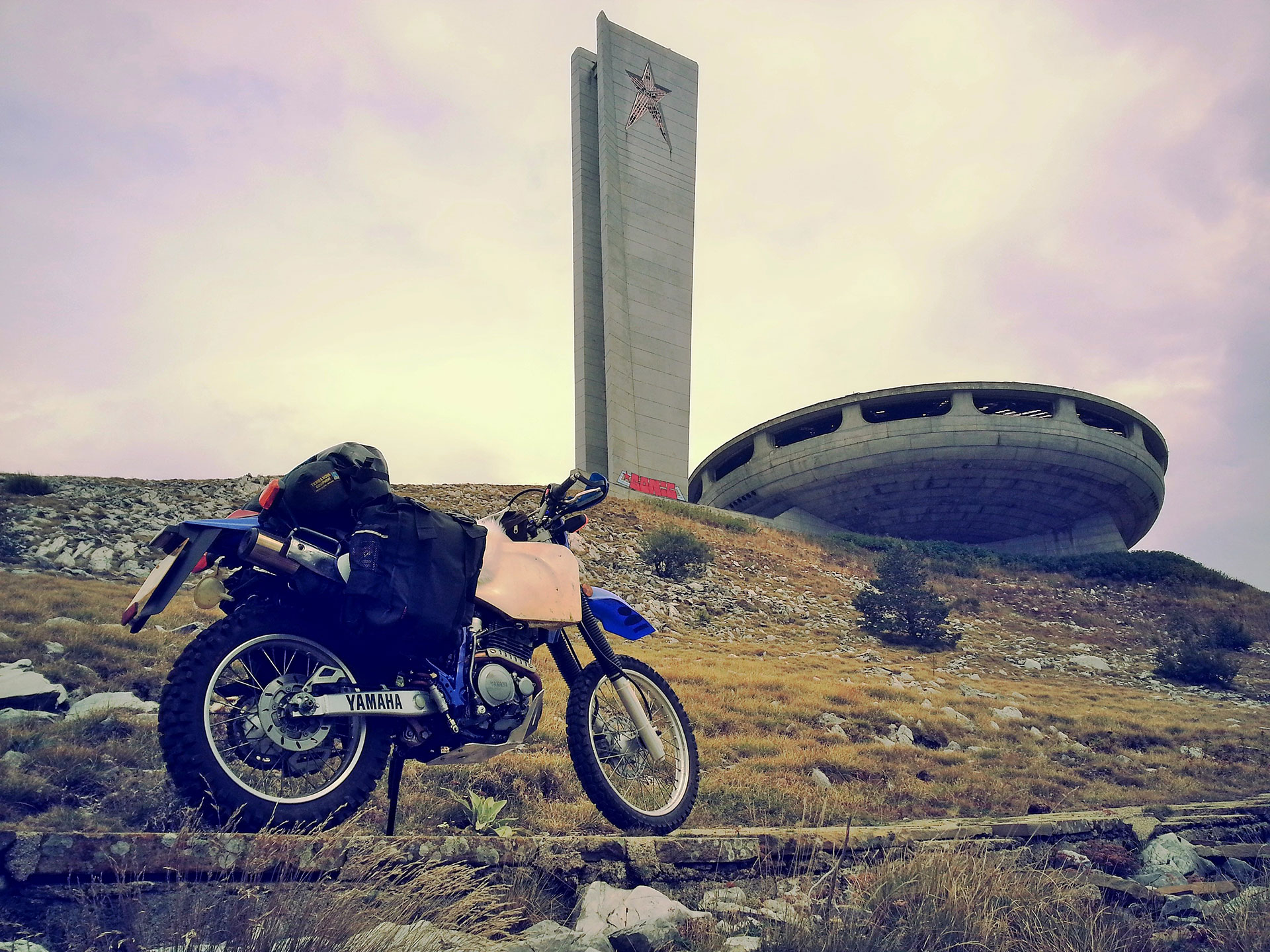 Lois Pryce's motorbike next to an abandoned Soviet-era UFO-shaped building in Bulgaria