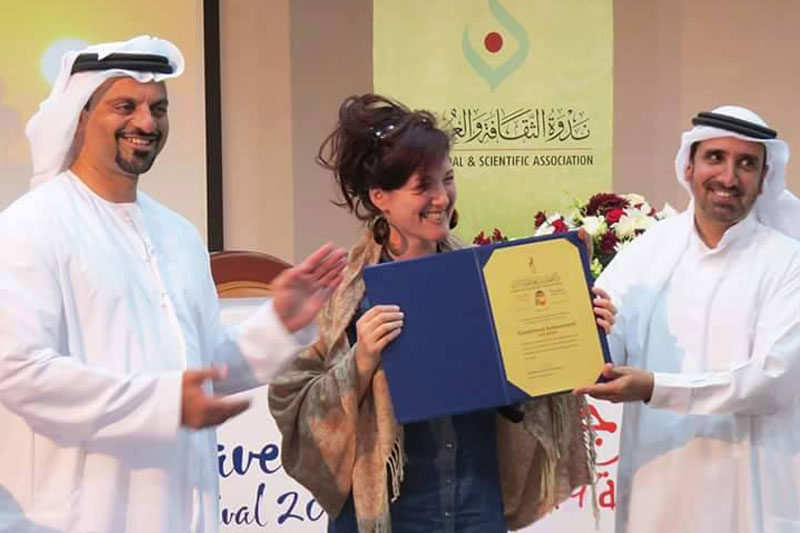 Lois Pryce receiving a journalism award from two Arabic men