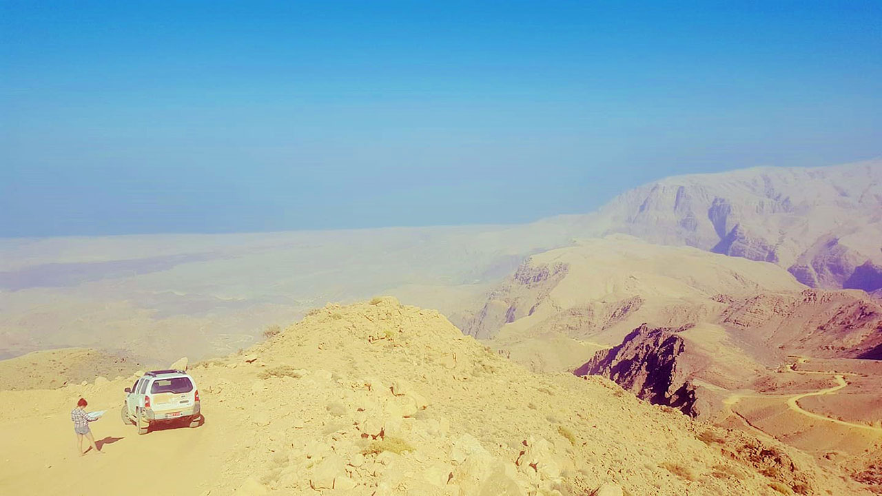 Mountains of Oman with travel writer Lois Pryce reading a map next to a jeep