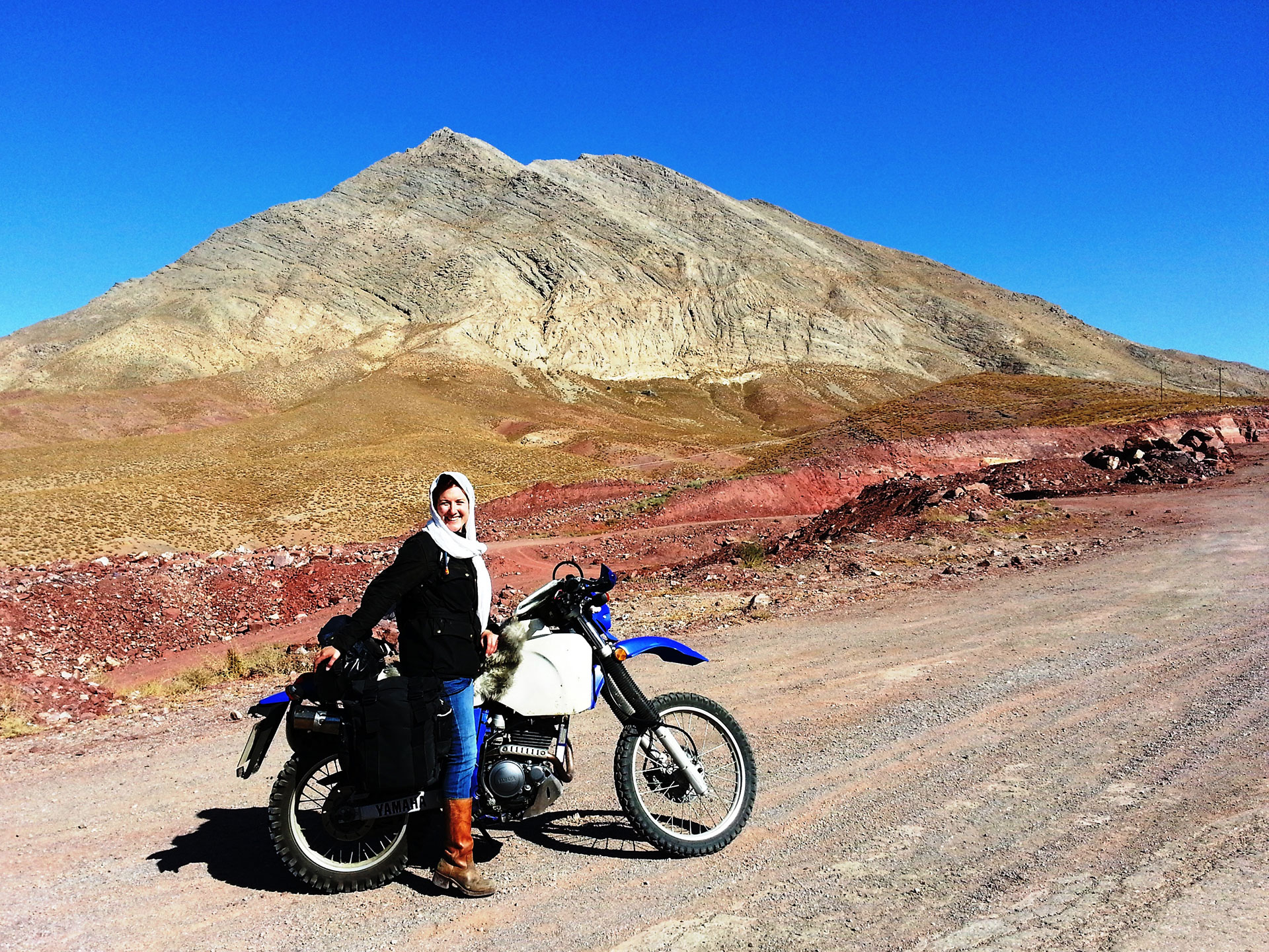 Motivational speaker Lois Pryce in the Iranian mountains with her motorbike, smiling
