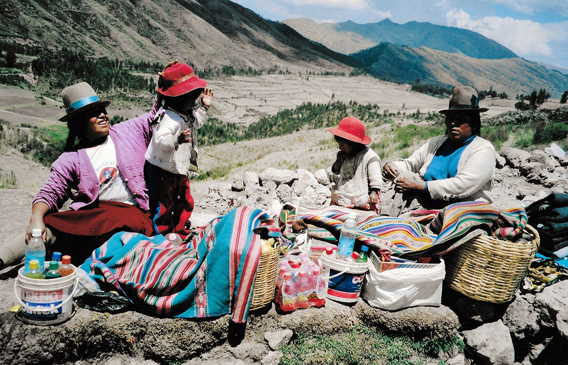 Peruvian women and children in hats with colourful blankets in the mountains