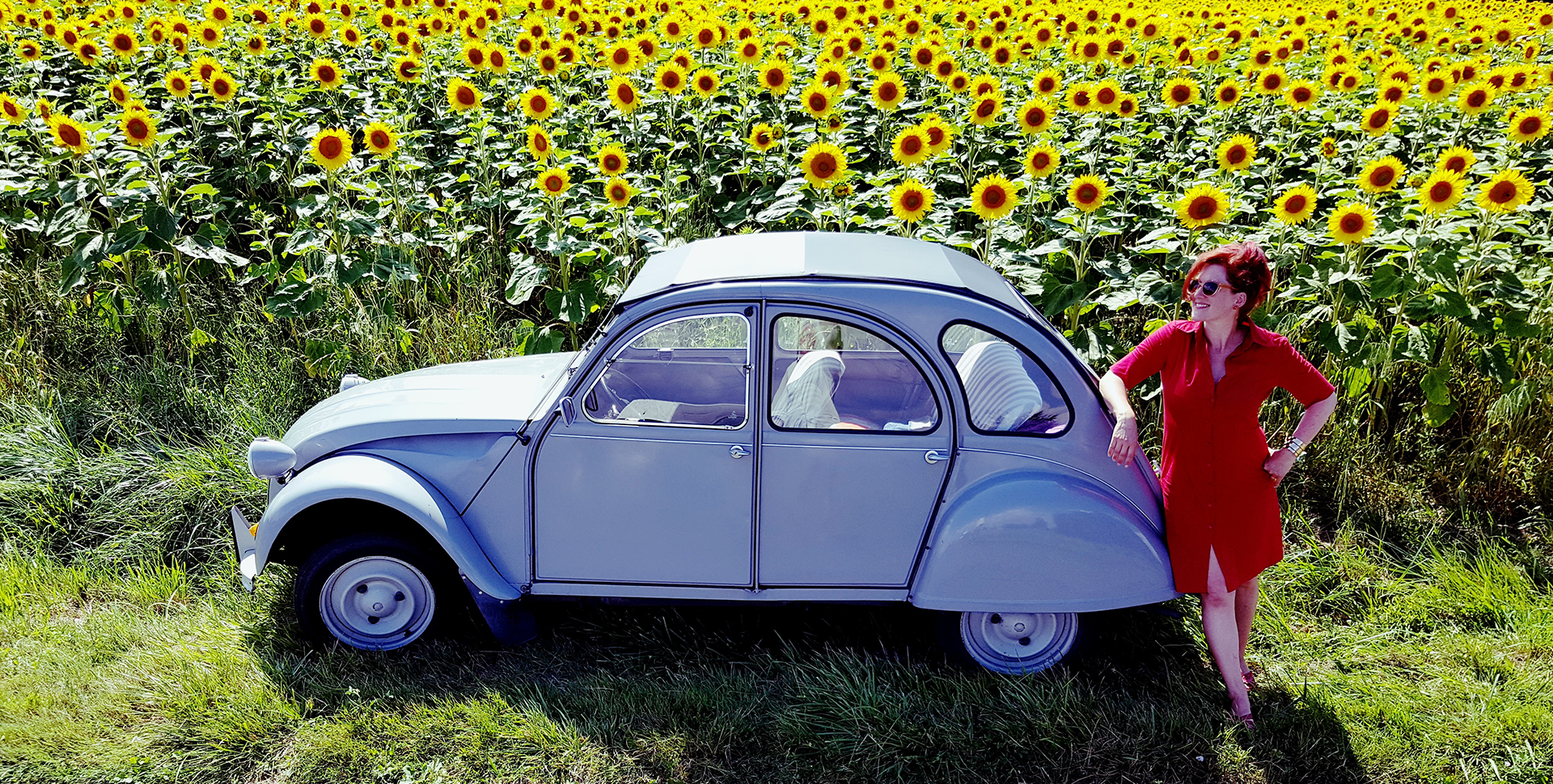 Female adventure speaker Lois Pryce by a 2CV car in a field of sunflowers